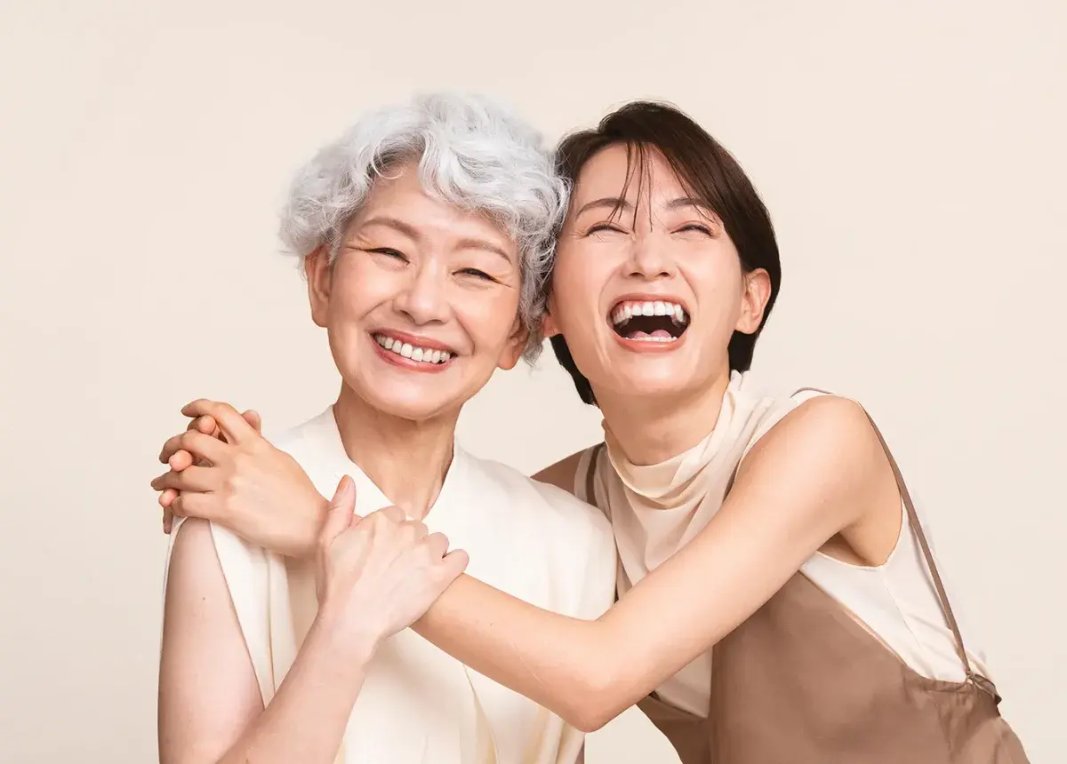 高齢の女性と若い女性が笑いながら寄り添っている様子